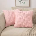 Fodera per cuscino in peluche rosa con motivo geometrico, esposta su un divano beige. - Rosa