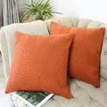 Zwei hochwertige orangefarbene Samtkissenbezüge mit Chevron-Steppmuster auf einem Sofa - 2-Teiliges Set / Orange