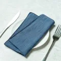 Blue cotton cloth napkin neatly folded on a white plate with cutlery - 32x32cm / Blue