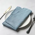 Elegant light blue slub cotton cloth napkin with overlocked edges on a white plate - 32x32cm (1 Piece) / Light Blue (CD260703-30)