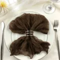 Elegant brown cheesecloth napkin with silver rings on white plate for wedding table decor - 44x44cm / Dark Coffee