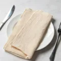 Beige bamboo cotton napkin folded on a white ceramic plate with silver cutlery - 32x32cm / Beige