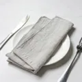 Elegant grey slub cotton napkin with overlock edges on a white dinner plate - 32x32cm (One Placemat) / Light Grey (CD260703-17)