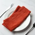 Textured rust orange cotton dinner napkin with fringed edges on a ceramic plate - 32x32cm (1 Piece) / Burnt Orange (CD260703-32)
