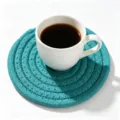 Handmade woven cotton rope coaster in teal, presented with a white coffee cup on white background - Diameter 11cm / Peacock Green (38)