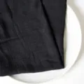 Hochwertige schwarze Serviette aus Baumwolle mit Faltenstruktur auf einem weißen Keramikteller - 32x32cm / Schwarz