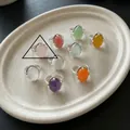 Draufsicht auf eine Auswahl an ovalen Edelsteinringen auf einem minimalistischen Keramiktablett - Hellviolett (J9470)