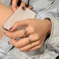 Minimalist 925 sterling silver knot ring showcased on a model hand holding a phone - Adjustable Open / Knot Combination Style (J951) / Silver