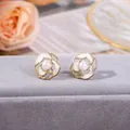 Dettaglio ravvicinato di orecchini a lobo a forma di camelia con perla bianca centrale - Orecchini