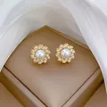 Dettaglio di eleganti orecchini a fiore in oro con perla centrale e petali di zirconi - Orecchini