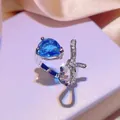 Primo piano di un anello d'argento con pietra a goccia blu e fiocco scintillante - Anello
