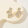 Primo piano di orecchini a lobo a petalo irregolare con bordi dorati e smalto perlato - Bianco