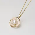 Primo piano di collana con ciondolo a camelia dorata e perla d'acqua dolce naturale - Collana