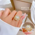 Dettaglio di un elegante anello d'oro con perla e fiore di zirconi scintillanti - Anello