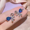 Dettaglio di orecchini a fiocco in argento con brillanti strass blu a forma di goccia - Orecchini