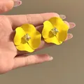 Dettaglio ravvicinato di orecchini a fiore giallo opaco con cristallo quadrato - Giallo