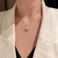 Vista dettagliata di un'elegante collana di perle dorate con ciondolo circolare in strass - Collana
