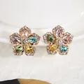 Close-up detail of elegant gold flower earrings with vibrant multi-colored zircon stones - Colorful
