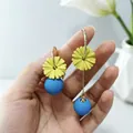 Primo piano di orecchini a margherita gialla asimmetrici con gocce di perle blu opache - A007不规则黄花珍珠