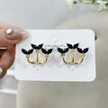 Primo piano di eleganti orecchini dorati con pietre nere a forma di foglia su carta - A008