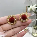 Primo piano dettagliato di orecchini floreali con pompon rossi e piccole perle bianche - A001 Rosso