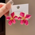 Eleganti orecchini a lobo floreali in smalto fucsia con centri dorati su una carta - Rosso rosa