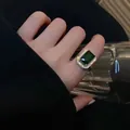 Anello vintage con cristallo verde smeraldo e alone di zirconi, visto al dito. - Anello
