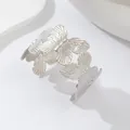 Vista ravvicinata di un ampio bracciale rigido argento con motivi a farfalla dettagliati - Farfalla Argento