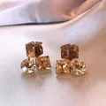 Detailaufnahme der champagnerfarbenen 3D-Würfel-Kristallohrringe auf weichem Satin-Hintergrund. - Geometrischer Strass-Patchwork-Stil (E3855) / Goldbraun