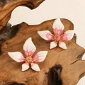 Vista dettagliata di orecchini a fiore a cinque petali in smalto rosa sfumato su legno - Rosa