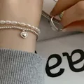 Κοντινό πλάνο ενός σετ βραχιολιών από ασήμι 925 με καρδιά και πέρλες για γυναίκες - Σετ Βραχιόλι με Στρώσεις Μαργαριταριών και Καρδιά (SL0724)