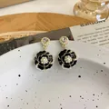 Primo piano di eleganti orecchini camelia nera con dettagli in perle e cristalli. - Modello lungo / Nero
