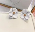 Macro detail of elegant white flower stud earrings with matte paint finish and gold center - White