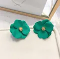 Dettaglio macro di orecchini a forma di fiore verde opaco con un centro dorato. - Verde