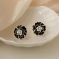 Dettaglio orecchini camelia neri con perle bianche su vassoio in ceramica bianca - Orecchini a lobo / Nero