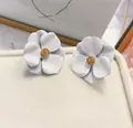 Eleganti orecchini a lobo a fiore bianco opaco con un centro dorato strutturato - Bianco