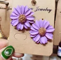 Vista macro dettagliata di orecchini a margherita viola con i centri dorati testurizzati - Viola