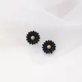 Detailed view of matte black daisy stud earrings featuring a textured golden center - Black
