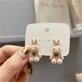 Dettaglio ravvicinato di graziosi orecchini in peluche a coniglio con piccoli fiocchi - Coniglio Beige
