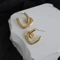 Close-up of elegant gold heart-shaped hoop earrings on white display stone - Gold