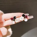 Dettaglio di orecchini a fiore vintage con zircone e piccoli fiori di rosa scura - Colorato