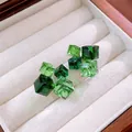 Dettaglio di orecchini a cubo geometrici con cristalli di zircone verde sfumato. - Verde