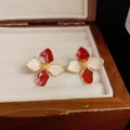 Dettaglio di orecchini a fiore in smalto rosso e crema in un portagioie di legno. - Lega / Rosso e Bianco Sporco