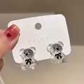 Dettaglio di orecchini a lobo a forma di orsetto in resina su cartoncino bianco - Transparent Panda/Bear