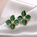 Primo piano di eleganti orecchini a lobo a fiore in smalto verde con bordi dorati - Lega / Verde