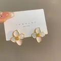 Dettaglio ravvicinato di eleganti orecchini a lobo a fiore bianco con centro dorato - Lega / Bianco