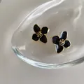 Eleganti orecchini a quadrifoglio in smalto nero con dettagli di stami dorati - Lega / Nero