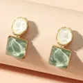 Macro dettagliata che mostra la trama a onde di questi orecchini quadrati verdi. - Verde