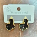 Close-up of geometric cloud stud earrings with black enamel and gold finish on card. - Geometric Cloud Style / Black