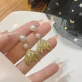Detailed shot of gold mermaid tail earrings featuring elegant white double pearls - Fish Tail Double Pearl Style / Gold (E3210)